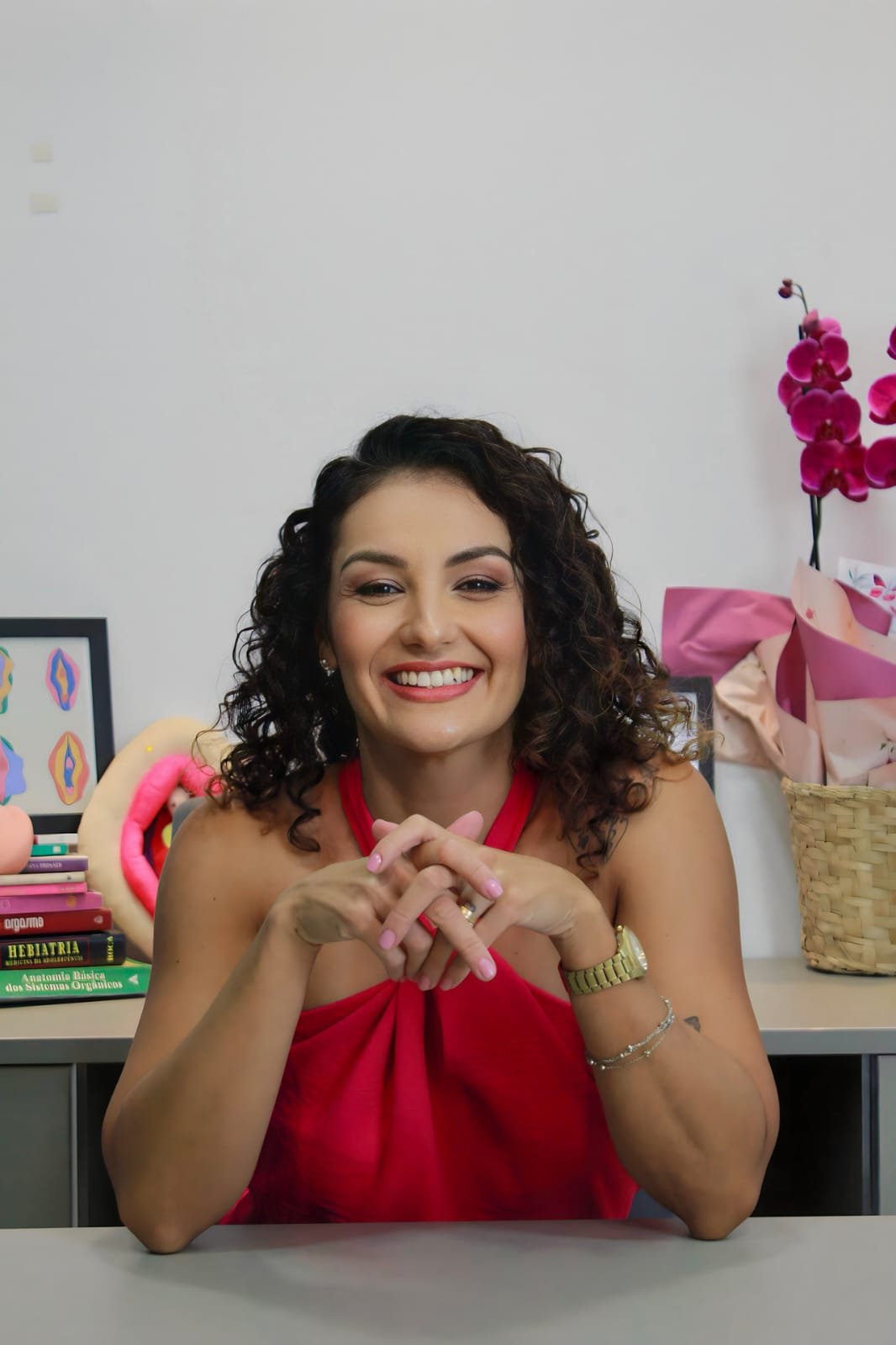 Drª Daniele Moreira sorrindo, com orquídeas ao fundo